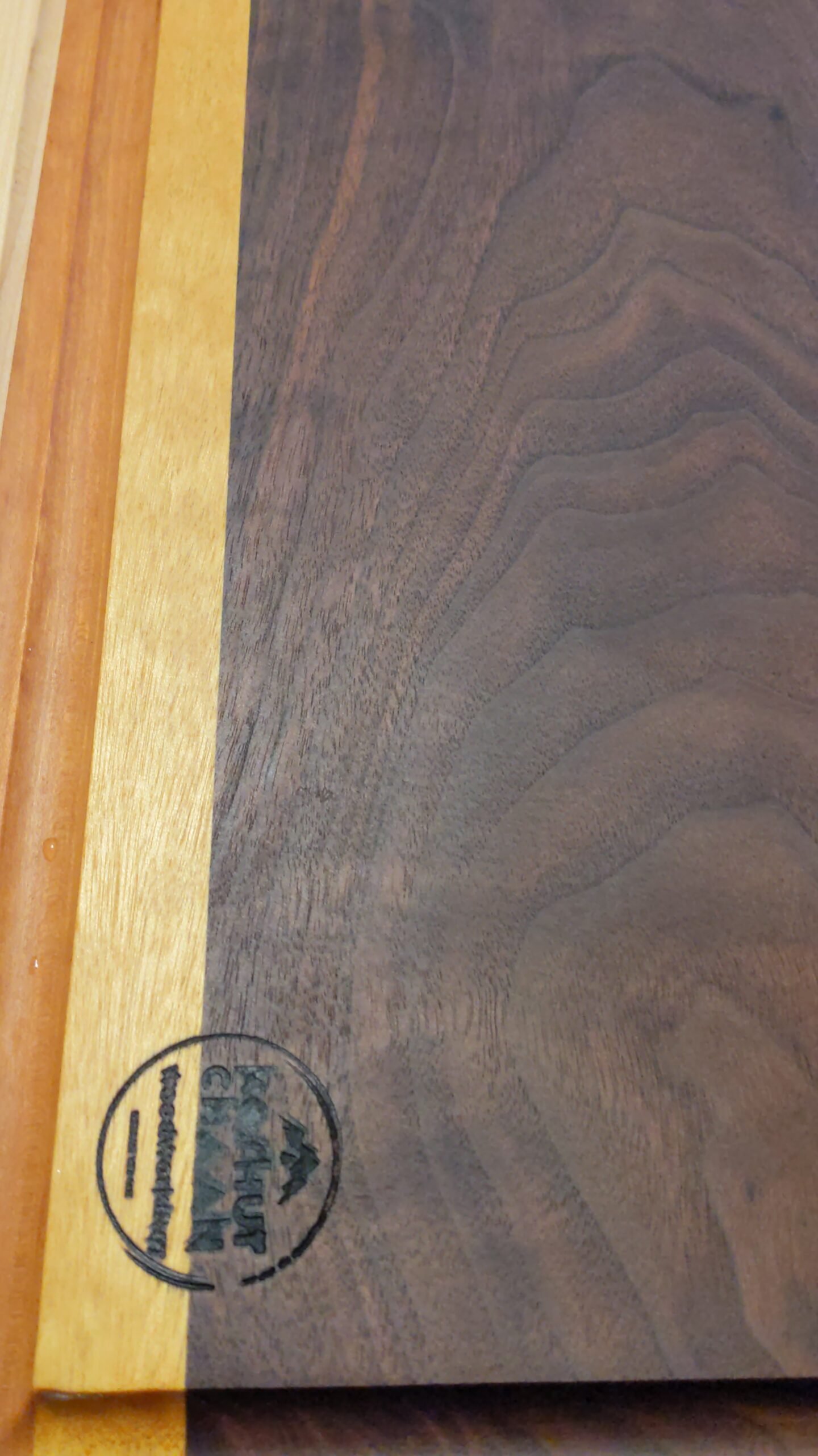 Koshur Chaan Woodworking 8 Close-up of a striped hardwood board with the Koshur Chaan maker’s mark