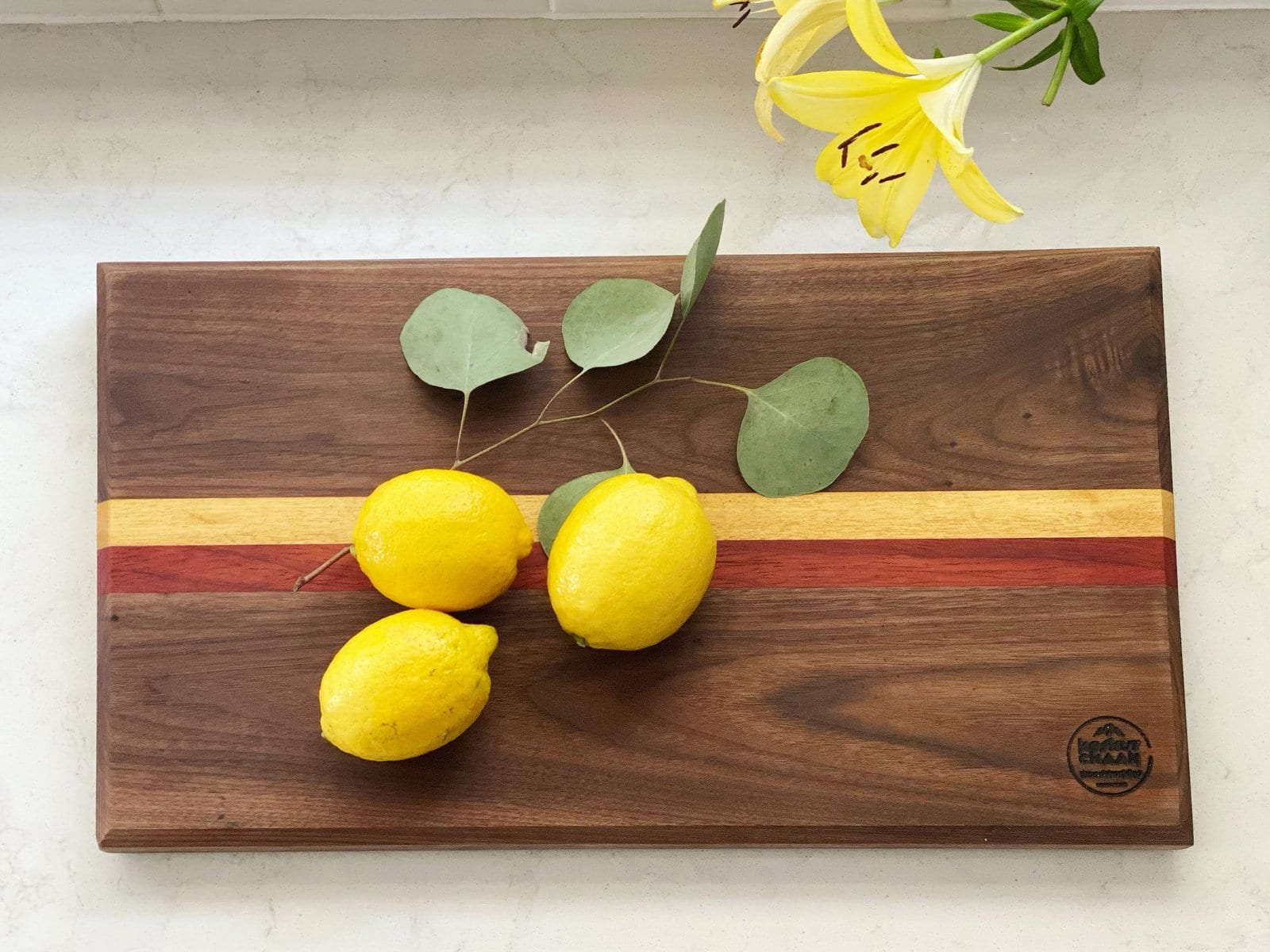 Koshur Chaan Woodworking 10 Walnut serving board with striped inlay, lemons and a yellow lily