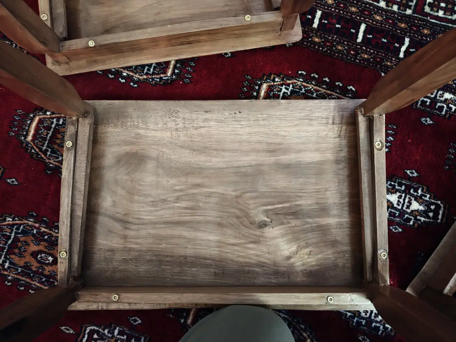 Underside of a Kashmiri walnut table showing unfinished surfaces and exposed screws