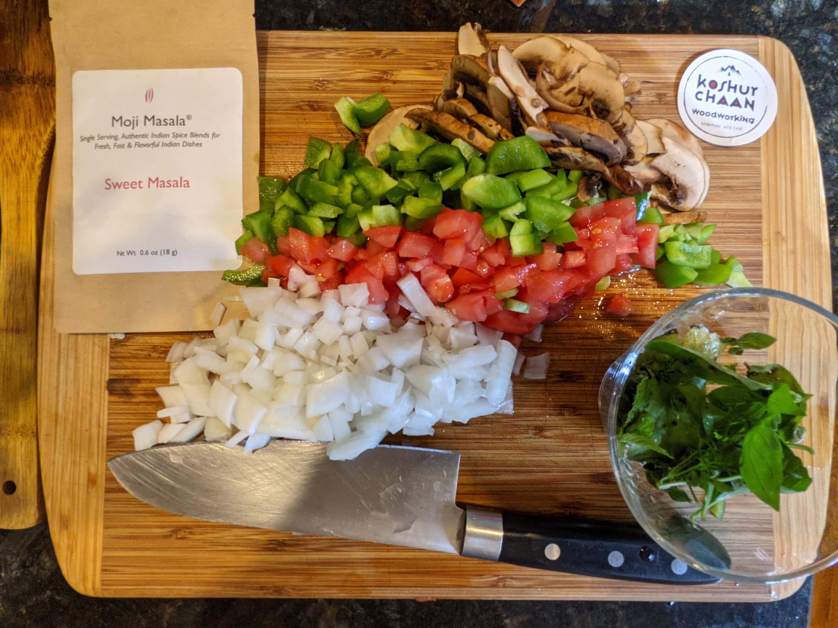 One of our handcrafted cutting boards in Duluth: cutting board covered with freshly chopped peppers, tomatoes, onion and herbs beside a chef's knife