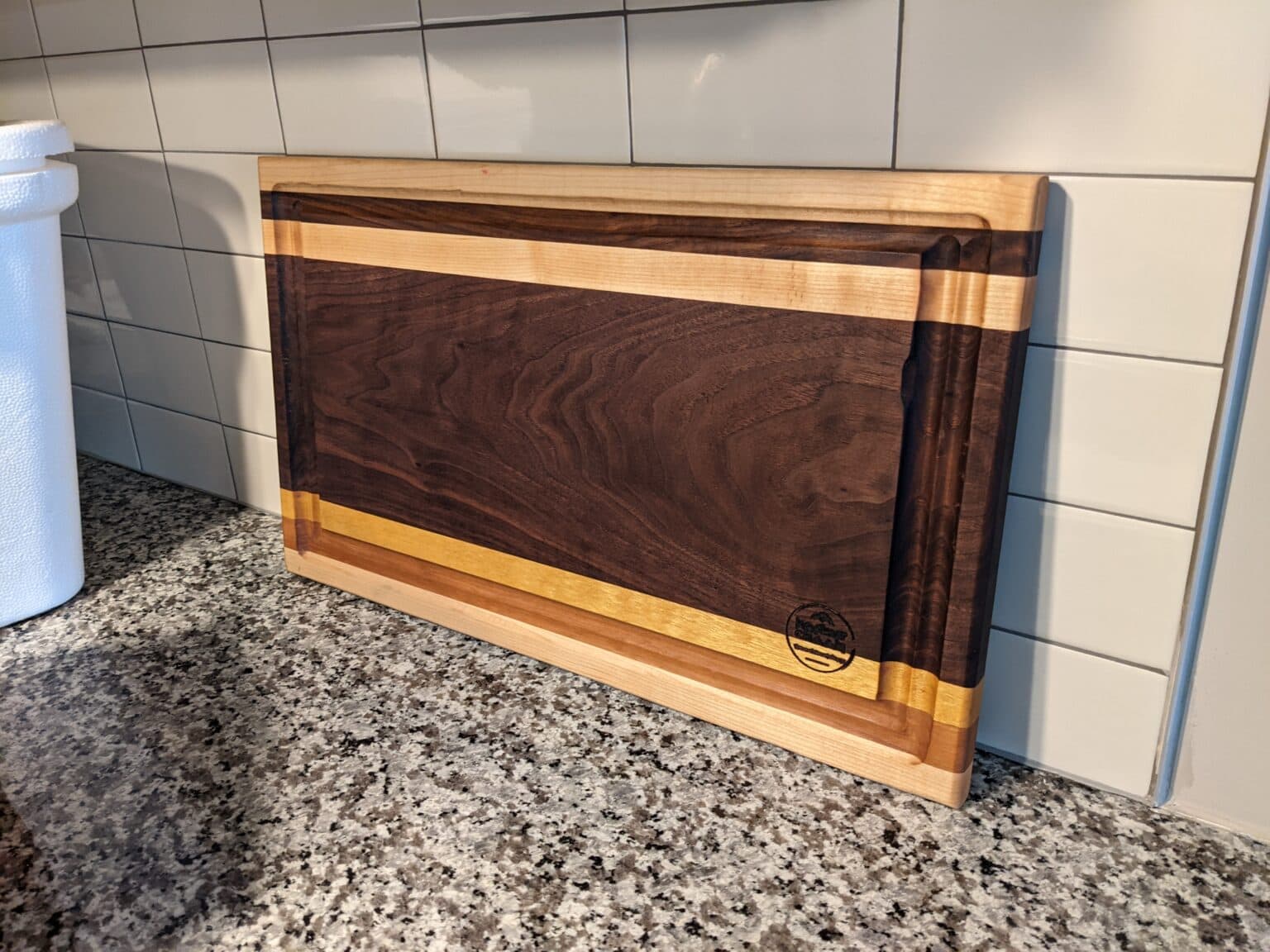 Walnut cutting board with maple edging on a granite kitchen counter