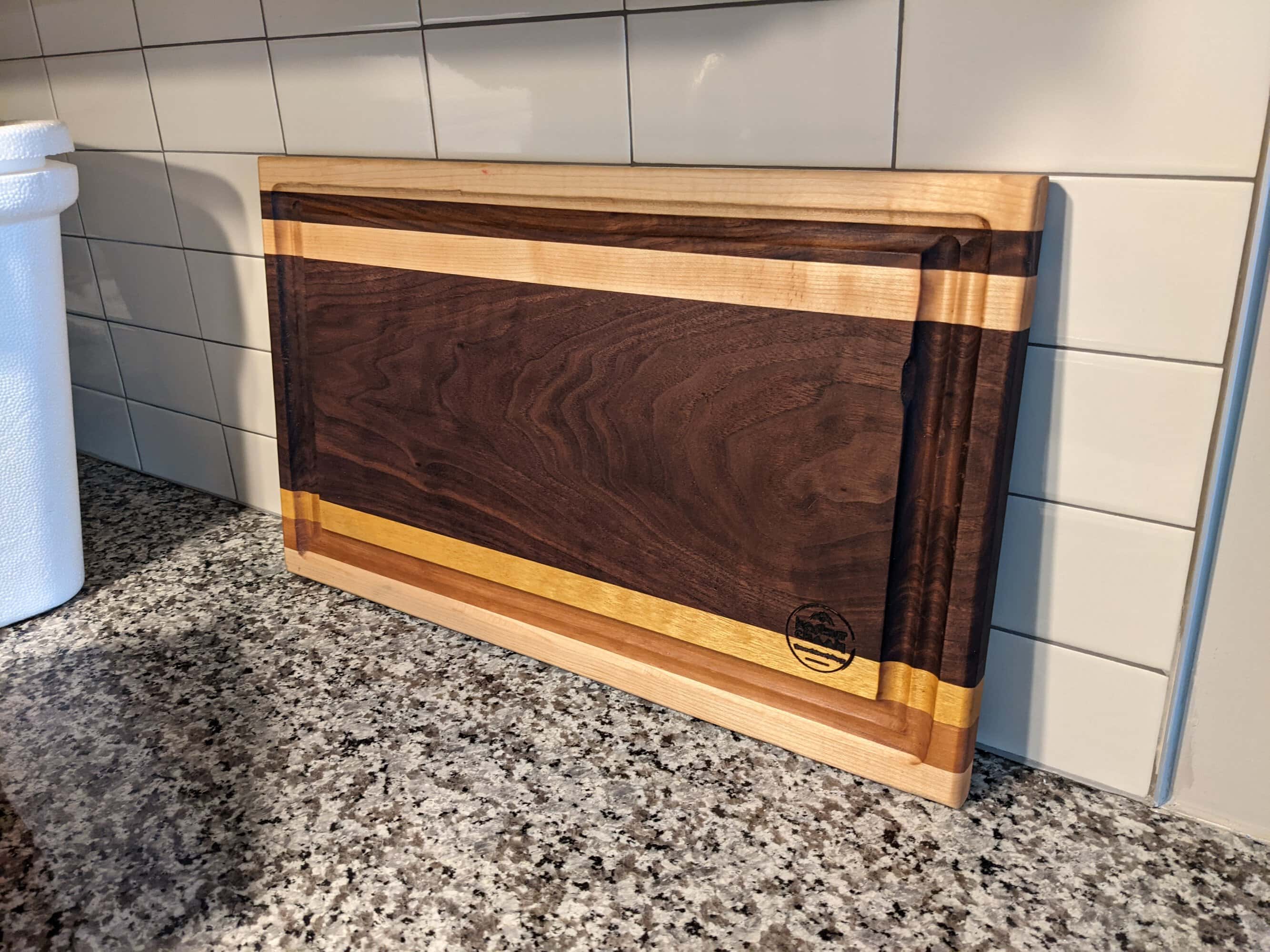 One of our handcrafted cutting boards in Buckhead: walnut cutting board with maple edging on a granite kitchen counter