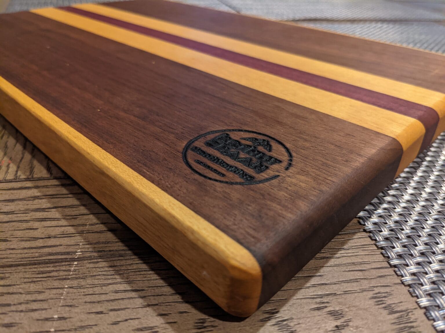 Oiling a cutting board: close-up of a walnut cutting board with maple and purple accent stripes and the Koshur Chaan stamp