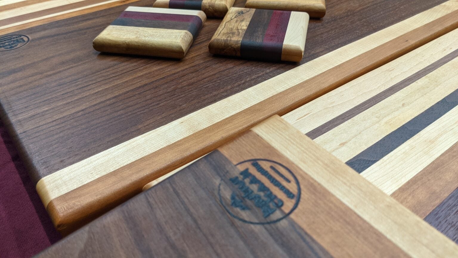 Square striped hardwood coasters resting on a walnut cutting board