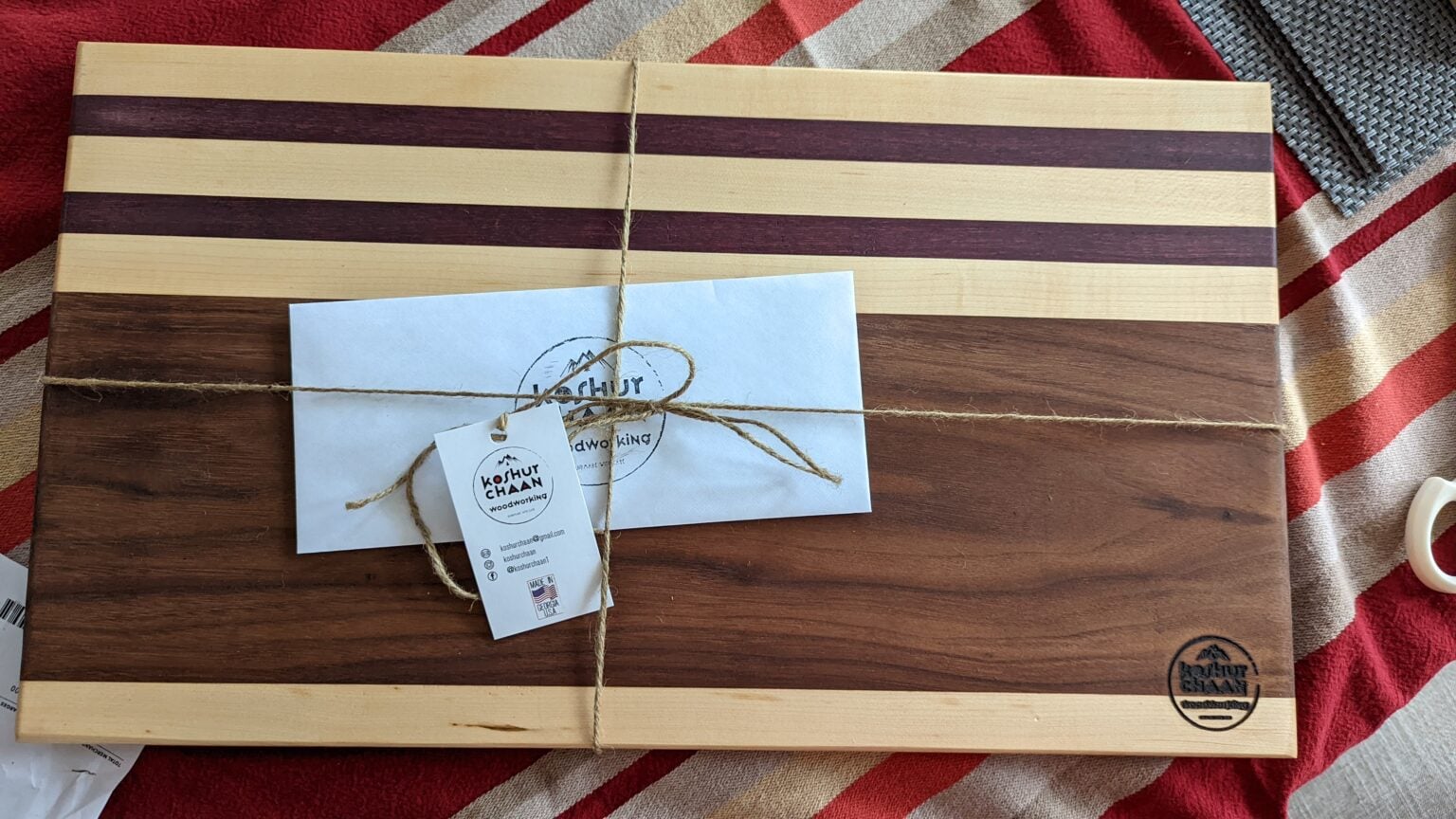 Striped walnut and maple cutting board wrapped with twine and a handwritten gift tag
