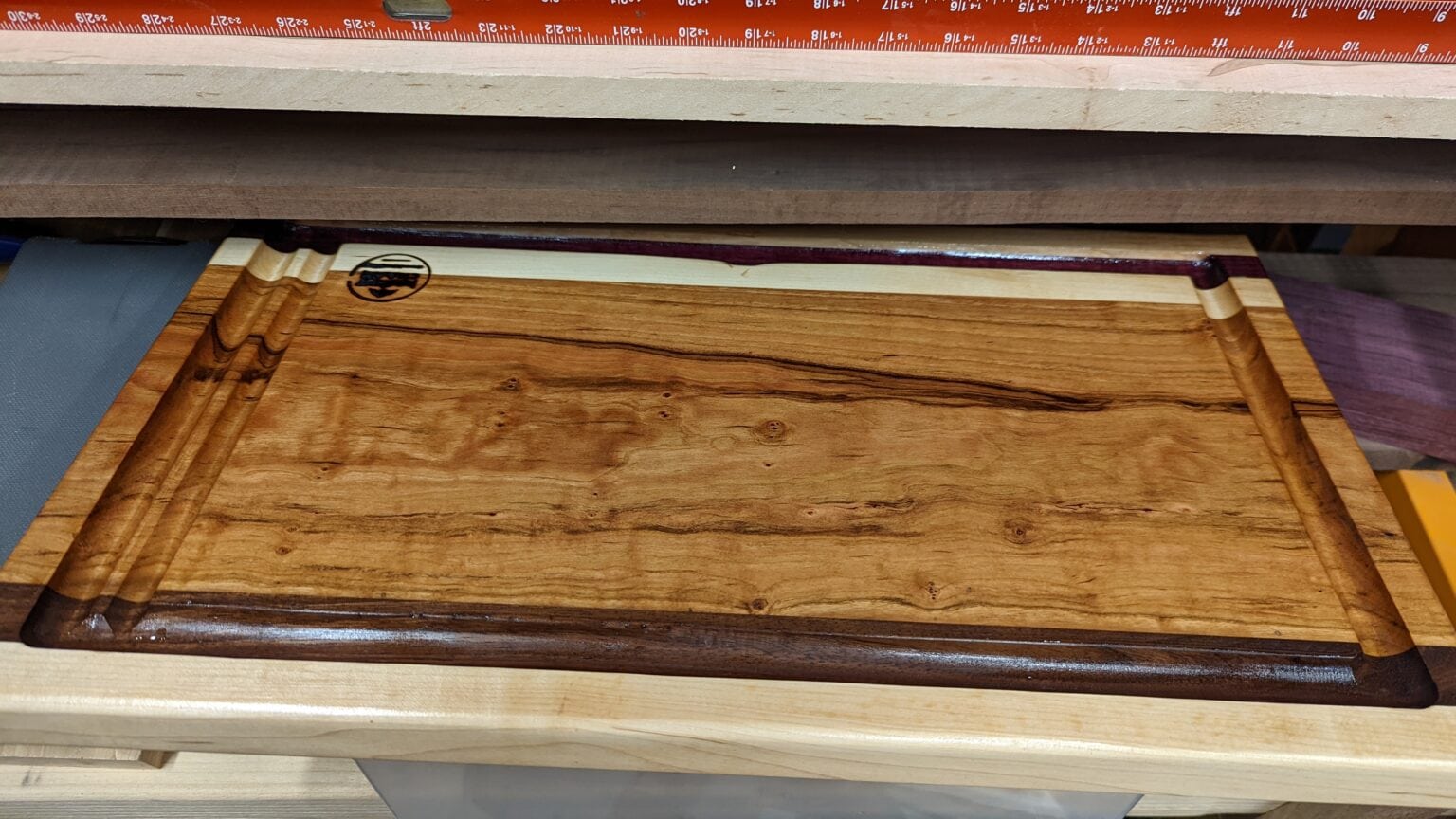 Figured hardwood serving board with a juice groove and maple edging