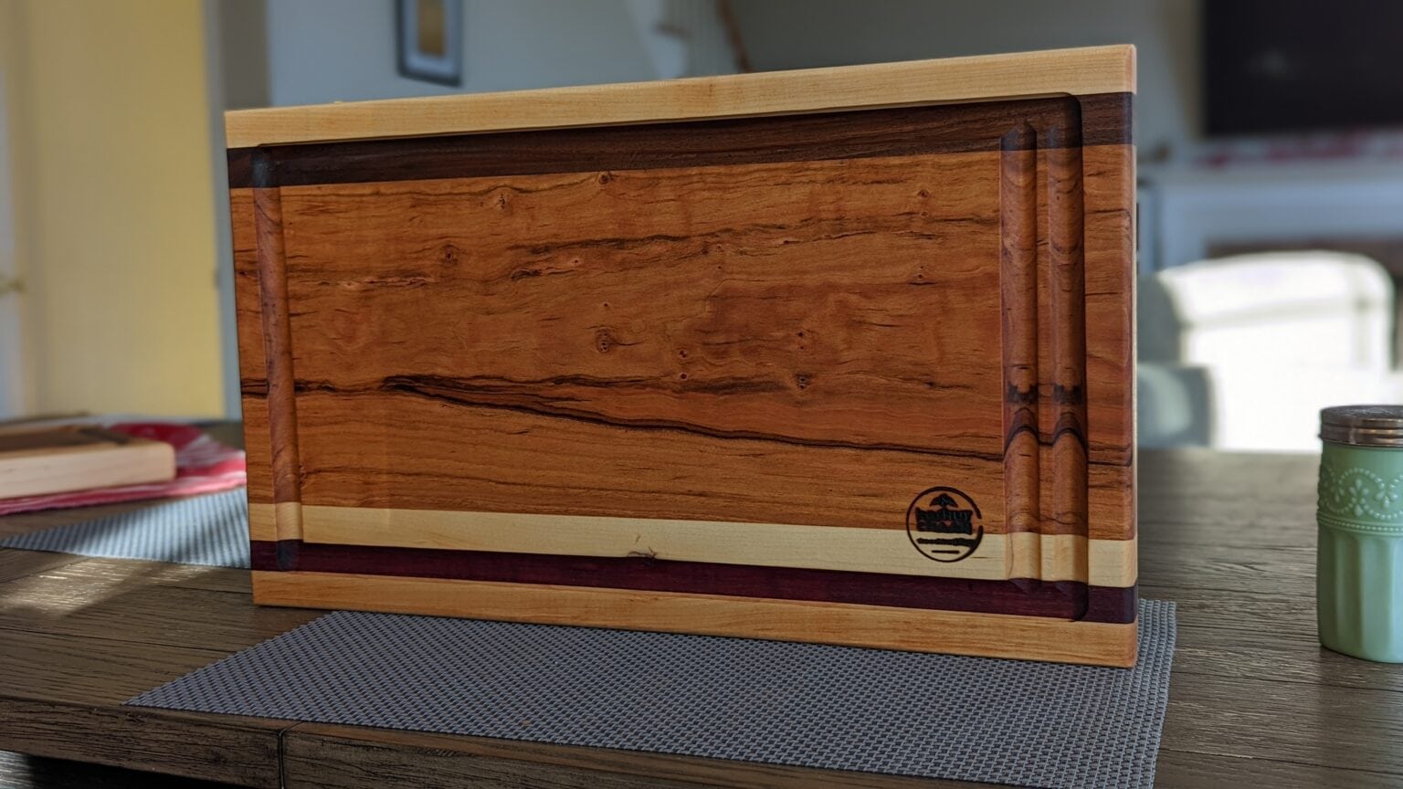 Figured hardwood cutting board with a juice groove and maple and walnut edging