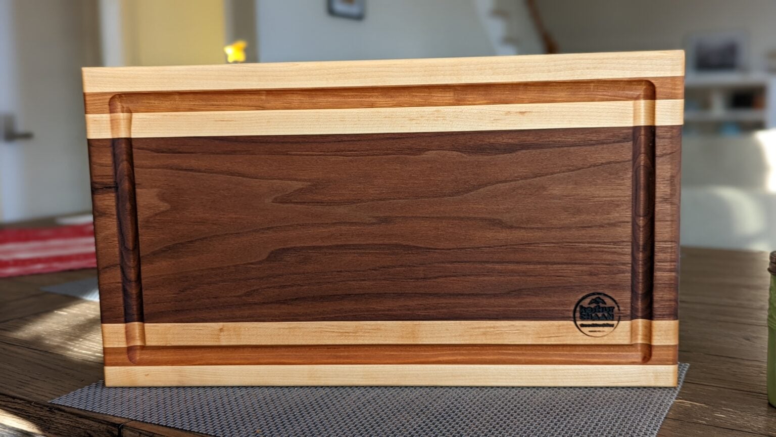 Walnut cutting board with a juice groove and maple edging on a woven placemat