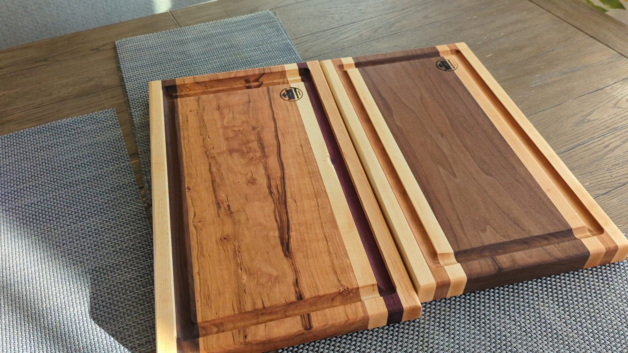 One of our handcrafted cutting boards in Atlanta: two striped hardwood cutting boards with juice grooves on a woven placemat