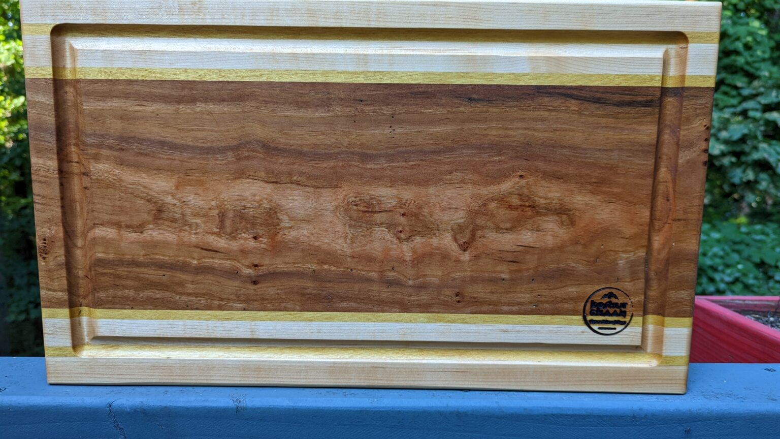 Why humans love natural wood: figured hardwood board with a juice groove and maple border on a blue railing