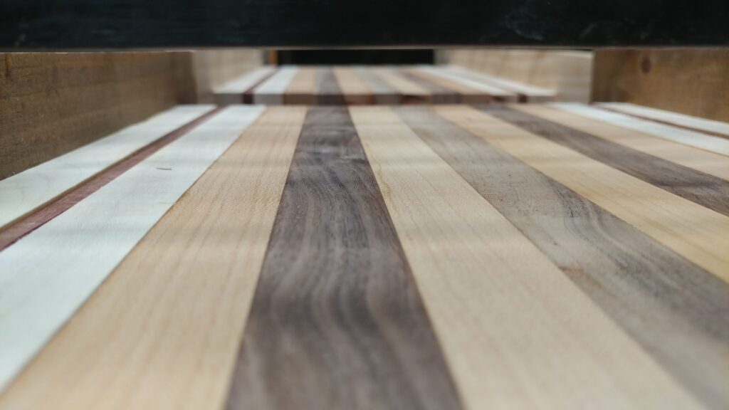 Close view of pale and brown wood strips with a narrow red accent in a cutting board