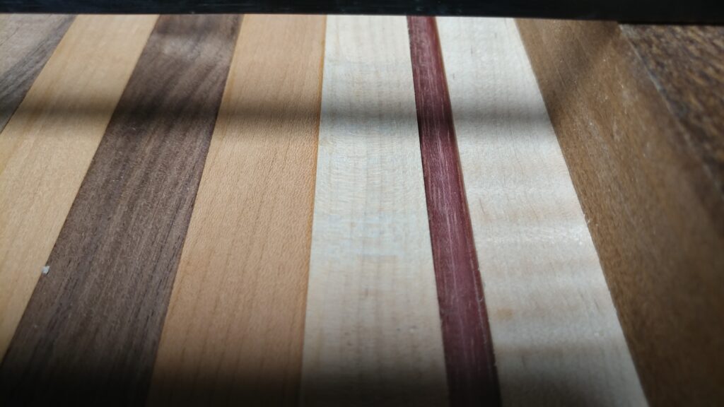 Close-up of alternating brown and pale wood strips with a narrow red accent stripe in a cutting board