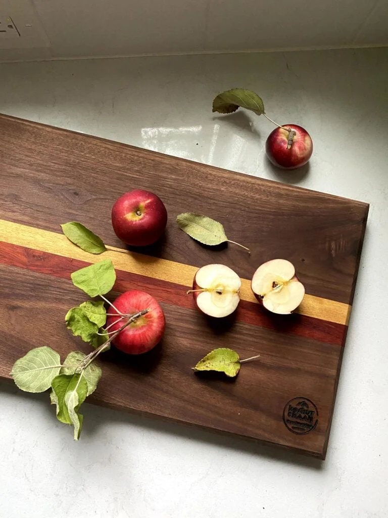 Red apples and apple halves on a dark wooden board with yellow and red accent stripes